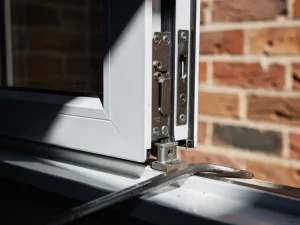 Wit uPVC raamkozijn met meerpuntssluiting en een verslagen koevoet op de vensterbank, Nederlandse bakstenen gevel op achtergrond.
