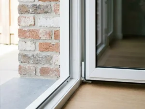 Wit PVC-raamkozijn in Nederlandse bakstenen muur met dorpeldrempel en strak afgewerkte onderzijde in natuurlijk daglicht.