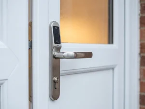 Witte uPVC voordeur met ingebouwd slim slot en geborsteld stalen cilinder, modern Nederlands woonhuis bij daglicht.